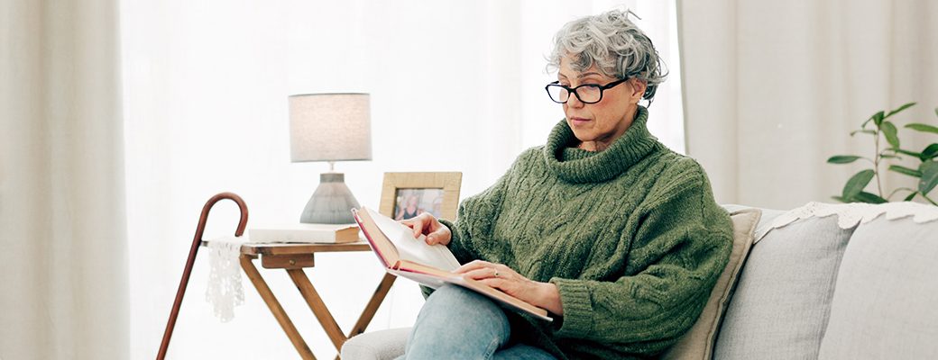 Image of senior woman sitting on the sofa and reading a book